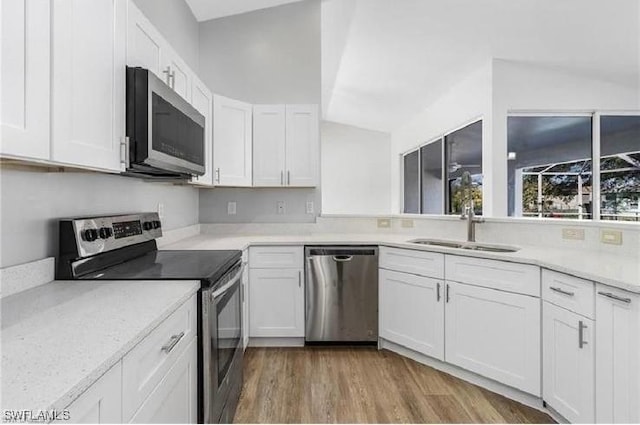 609 SW 22nd St, Cape Coral, FL 33991 - kitchen with appliances with stainless steel finishes, white cabinets, wood finished floors, light countertops, and vaulted ceiling