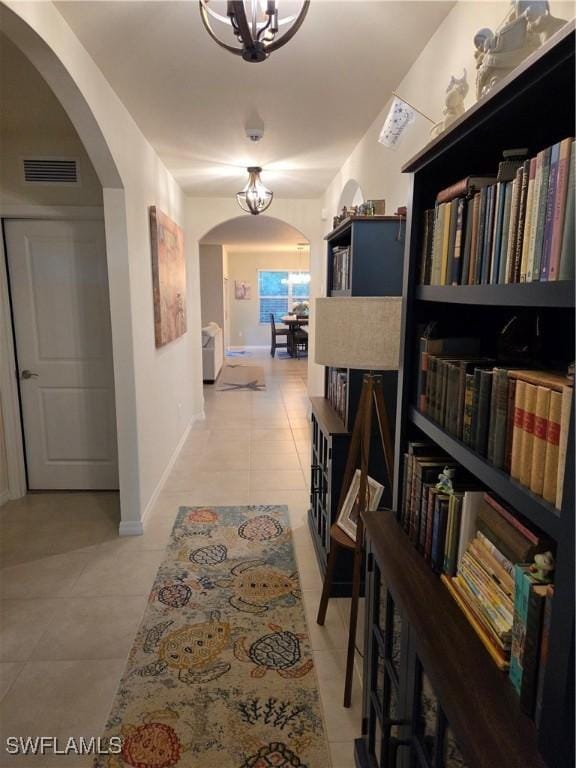 8868 E Cascade Price Cir, North Fort Myers, FL 33917 - hall featuring arched walkways, light tile patterned flooring, and a chandelier