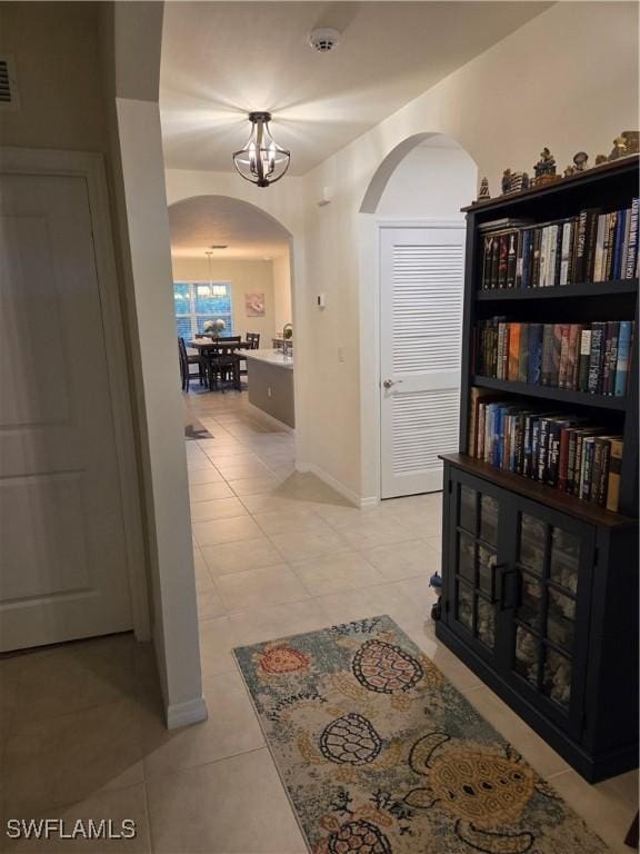 8868 E Cascade Price Cir, North Fort Myers, FL 33917 - corridor featuring arched walkways, a chandelier, and light tile patterned floors