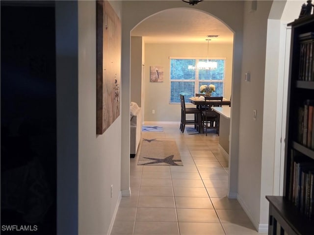 8868 E Cascade Price Cir, North Fort Myers, FL 33917 - hall featuring light tile patterned floors, a chandelier, and arched walkways