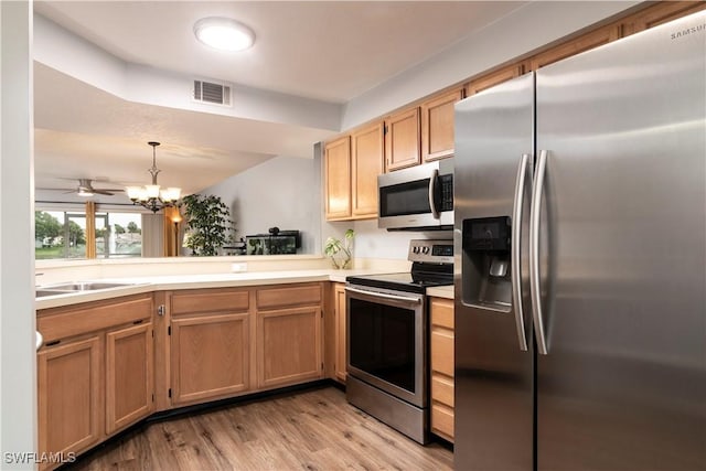 9580 Victoria Ln Unit A106, Naples, FL 34109 - kitchen with appliances with stainless steel finishes, light wood-style floors, a chandelier, light countertops, and hanging light fixtures