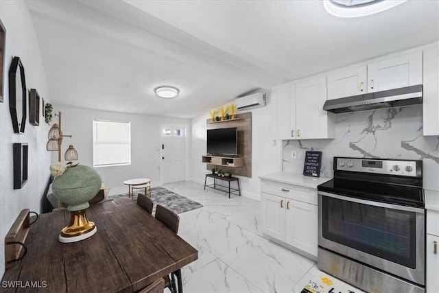 3064 Connecticut Ave, Naples, FL 34112 - kitchen with stainless steel electric range oven, under cabinet range hood, light marble finish flooring, an AC wall unit, and white cabinets