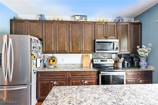 4440 40th St NE, Naples, FL 34120 - kitchen featuring stainless steel appliances, light stone countertops, and dark brown cabinetry