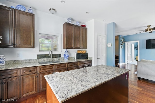 4440 40th St NE, Naples, FL 34120 - kitchen featuring open floor plan, light stone counters, a kitchen island, dark wood-type flooring, and ceiling fan