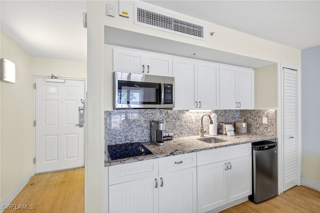 140 Estero Blvd Unit 2209, Fort Myers Beach, FL 33931 - kitchen featuring appliances with stainless steel finishes, light wood finished floors, tasteful backsplash, and white cabinetry