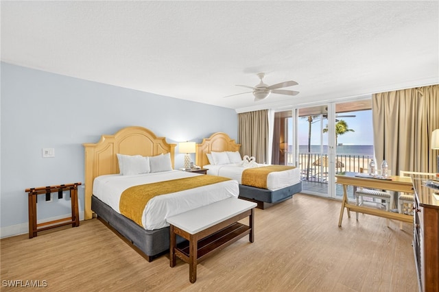 140 Estero Blvd Unit 2209, Fort Myers Beach, FL 33931 - bedroom with access to outside, light wood-style flooring, a water view, a wall of windows, and ceiling fan