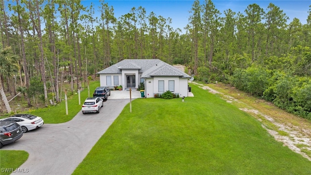 4267 4th Ave SE, Naples, FL 34117 - view of front of home featuring a forest view, a front lawn, stucco siding, roof with shingles, and driveway