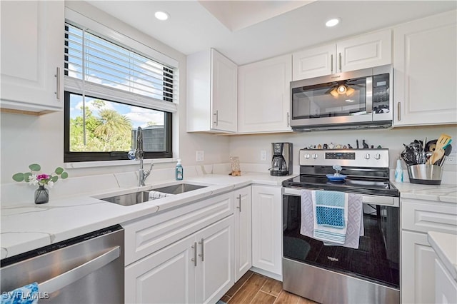 6296 Sugar Bush Ln Unit A, Fort Myers, FL 33908 - kitchen featuring appliances with stainless steel finishes, white cabinetry, recessed lighting, wood finished floors, and light stone counters