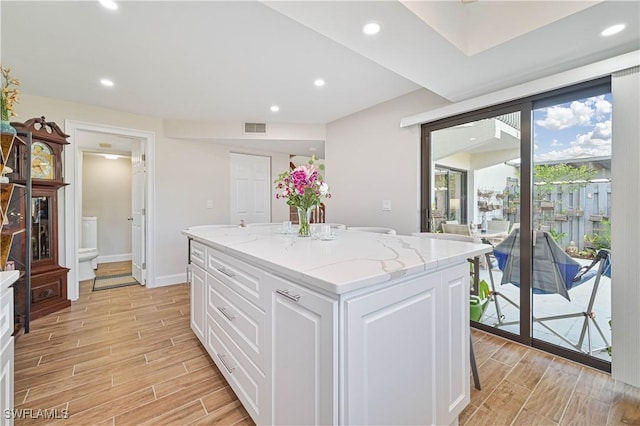 6296 Sugar Bush Ln Unit A, Fort Myers, FL 33908 - kitchen with wood finish floors, white cabinets, a kitchen island, light stone counters, and recessed lighting