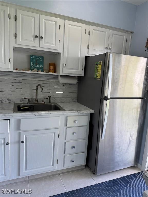 190 N Collier Blvd Unit O4, Marco Island, FL 34145 - kitchen featuring freestanding refrigerator, open shelves, white cabinets, light tile patterned floors, and tasteful backsplash