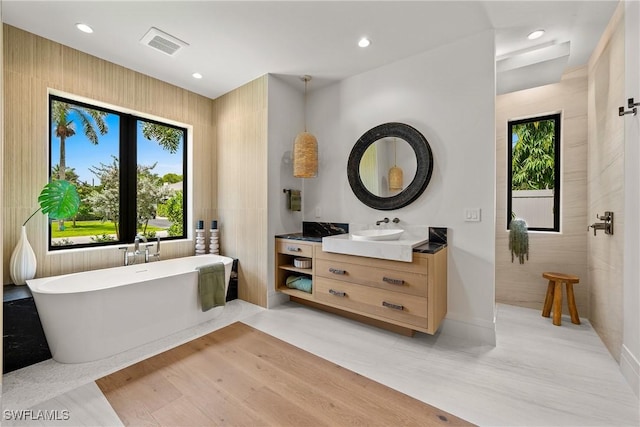 1261 13th Ave N, Naples, FL 34102 - full bath featuring vanity, a freestanding bath, recessed lighting, and wood finished floors
