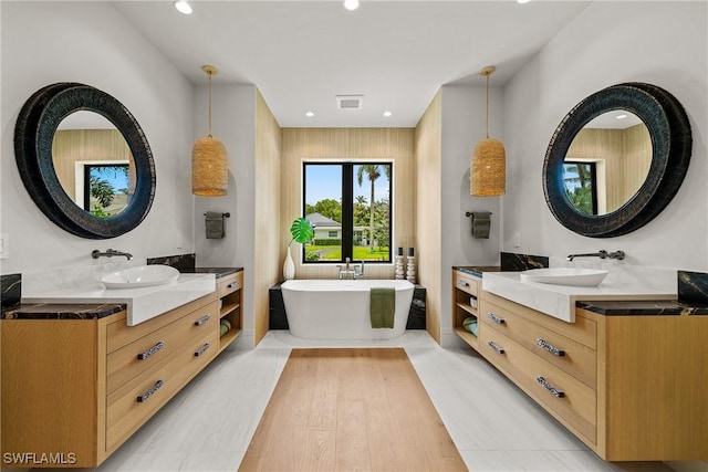 1261 13th Ave N, Naples, FL 34102 - full bath featuring two vanities, a freestanding bath, recessed lighting, and wood finished floors