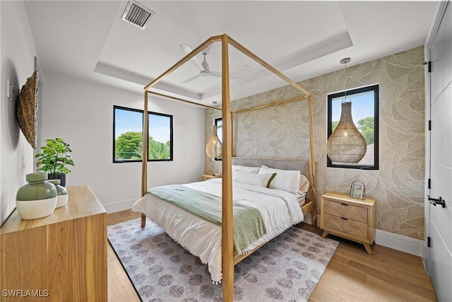 1261 13th Ave N, Naples, FL 34102 - bedroom with a tray ceiling, multiple windows, wood finished floors, and wallpapered walls