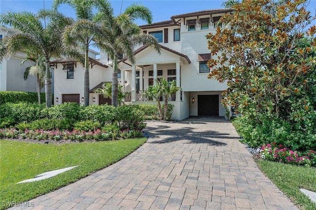 434 Trade Winds Ave, Naples, FL 34108 - view of front facade featuring decorative driveway, stucco siding, an attached garage, and a front yard