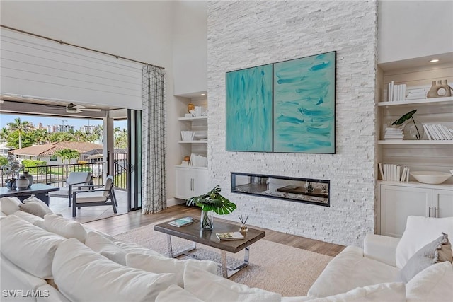 434 Trade Winds Ave, Naples, FL 34108 - living area featuring wood finished floors, a stone fireplace, a towering ceiling, ceiling fan, and built in features