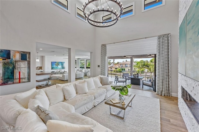 434 Trade Winds Ave, Naples, FL 34108 - living room with wood finished floors, a chandelier, a towering ceiling, and a stone fireplace