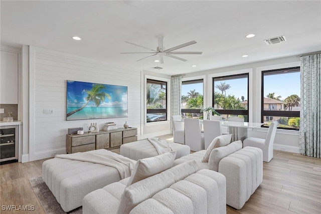434 Trade Winds Ave, Naples, FL 34108 - living area with light wood-style floors, a ceiling fan, wine cooler, recessed lighting, and wood walls