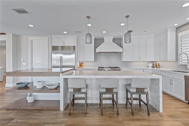 434 Trade Winds Ave, Naples, FL 34108 - kitchen featuring built in refrigerator, custom range hood, white cabinetry, decorative backsplash, and range