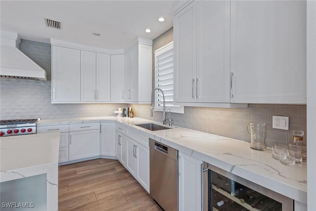 434 Trade Winds Ave, Naples, FL 34108 - kitchen featuring wine cooler, custom range hood, white cabinetry, dishwasher, and light wood-type flooring
