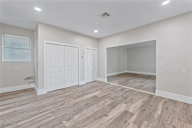 434 Trade Winds Ave, Naples, FL 34108 - unfurnished bedroom with two closets, light wood-style floors, and recessed lighting