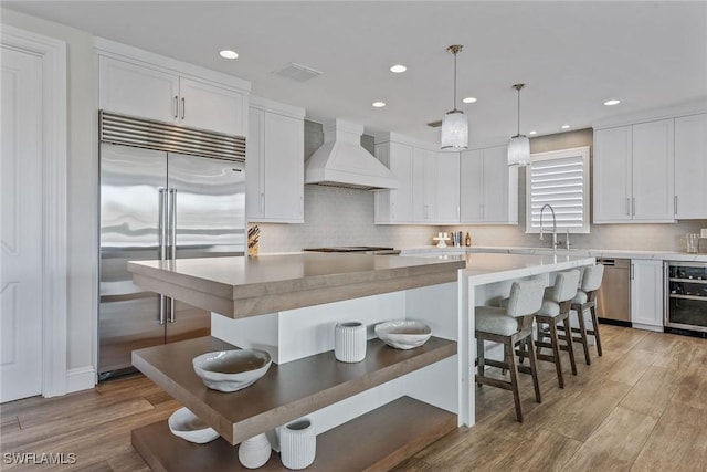 434 Trade Winds Ave, Naples, FL 34108 - kitchen with stainless steel appliances, white cabinetry, light wood-type flooring, tasteful backsplash, and recessed lighting