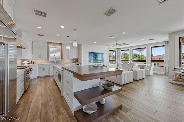 434 Trade Winds Ave, Naples, FL 34108 - kitchen with built in appliances, open floor plan, light wood finished floors, white cabinets, and recessed lighting