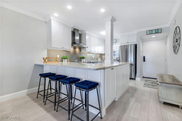 1208 Edington Pl Unit E204, Marco Island, FL 34145 - kitchen with wall chimney exhaust hood, freestanding refrigerator, a peninsula, white cabinets, and backsplash