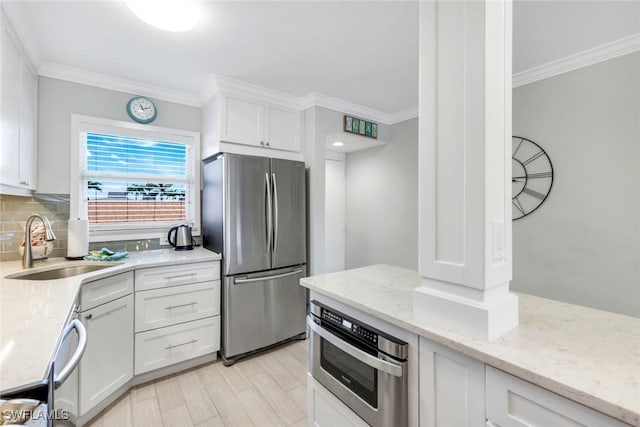1208 Edington Pl Unit E204, Marco Island, FL 34145 - kitchen featuring appliances with stainless steel finishes, crown molding, white cabinets, light stone countertops, and backsplash