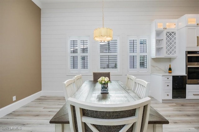 9088 Caicos Way, Naples, FL 34114 - dining space featuring light wood-style flooring, a chandelier, wooden walls, and wine cooler