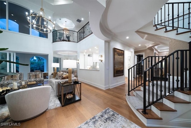 33 3rd St S, Naples, FL 34102 - living room featuring a chandelier, wood finished floors, crown molding, stairway, and a high ceiling