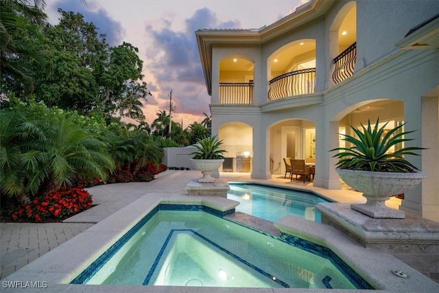 33 3rd St S, Naples, FL 34102 - pool at dusk featuring a pool with connected hot tub and a patio