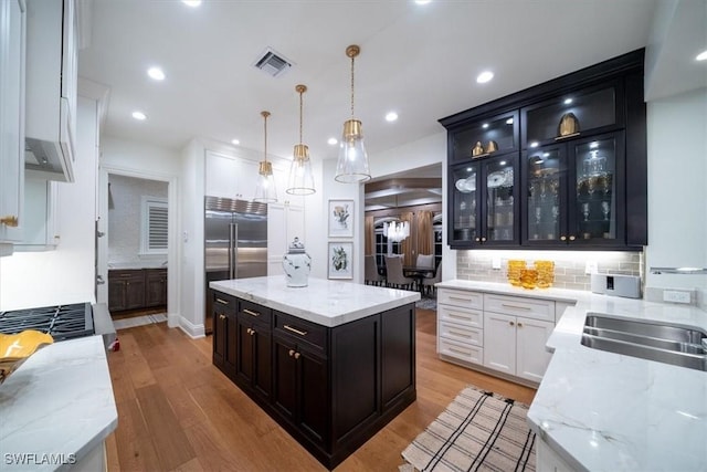 33 3rd St S, Naples, FL 34102 - kitchen with dark cabinets, light wood-style floors, decorative backsplash, a center island, and recessed lighting