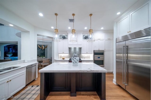 33 3rd St S, Naples, FL 34102 - kitchen with stainless steel appliances, decorative backsplash, white cabinetry, light wood-style flooring, and recessed lighting