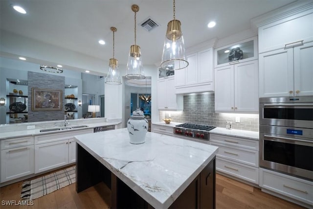 33 3rd St S, Naples, FL 34102 - kitchen featuring a kitchen island, decorative backsplash, wood finished floors, recessed lighting, and hanging light fixtures