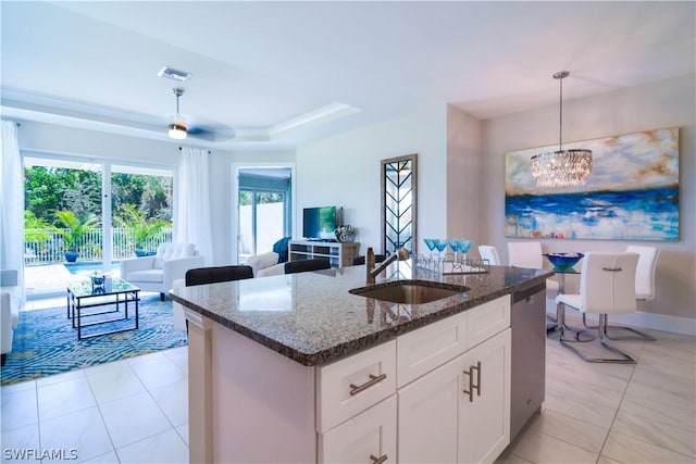 kitchen featuring pendant lighting, sink, white cabinets, dark stone countertops, and a notable chandelier