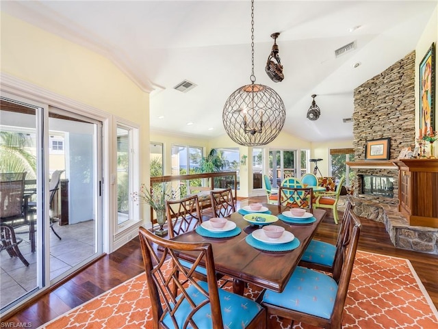 dining room featuring vaulted ceiling, dark wood-type flooring, a healthy amount of sunlight, and a fireplace