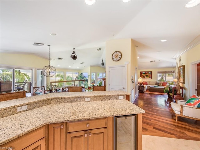 kitchen with wine cooler, hanging light fixtures, vaulted ceiling, light stone countertops, and dark wood-type flooring