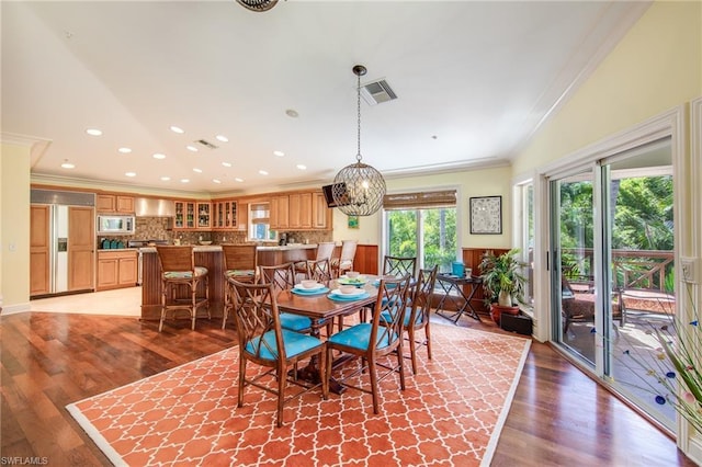 dining space with a chandelier, ornamental molding, and wood-type flooring