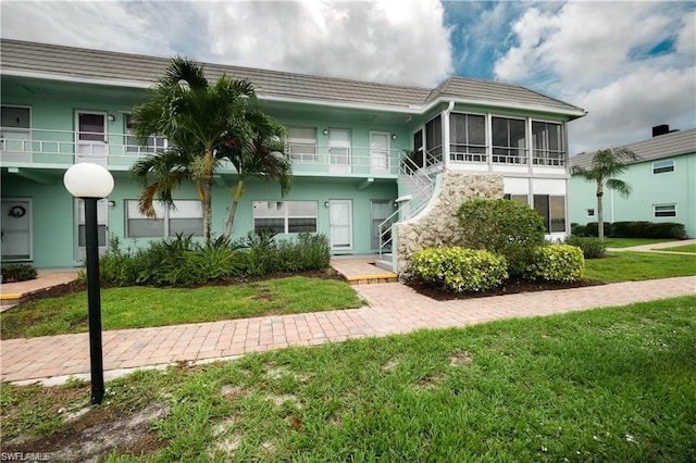 view of front of home featuring a balcony, a front yard, and a sunroom