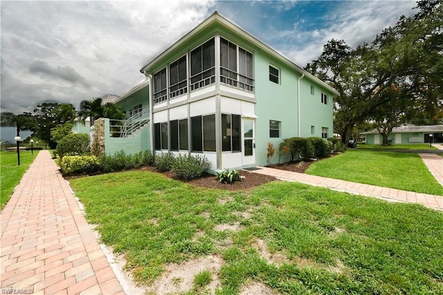 back of house featuring a lawn and a sunroom