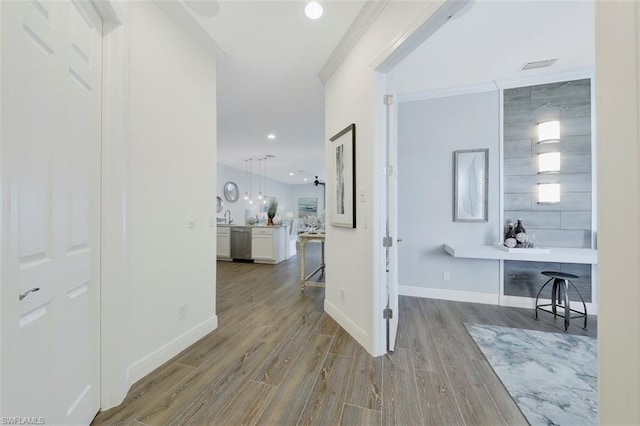 hallway featuring ornamental molding and light hardwood / wood-style flooring