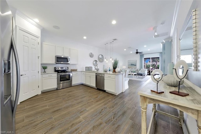 kitchen featuring hanging light fixtures, dark wood-type flooring, ceiling fan, appliances with stainless steel finishes, and white cabinets