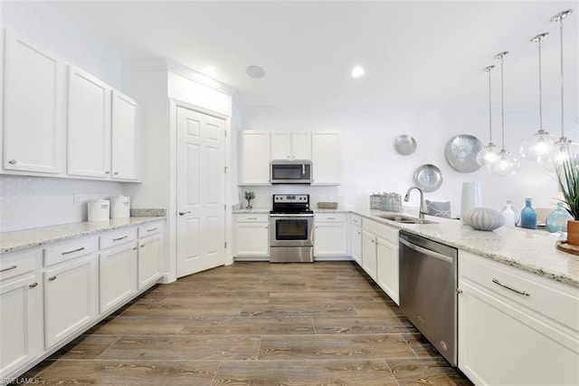 kitchen featuring hardwood / wood-style floors, hanging light fixtures, appliances with stainless steel finishes, sink, and white cabinets