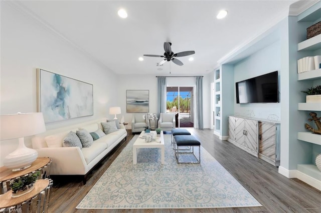 living room with built in features, ceiling fan, dark hardwood / wood-style floors, and crown molding