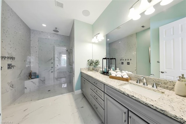 bathroom featuring double sink, tiled shower, vanity with extensive cabinet space, and tile flooring