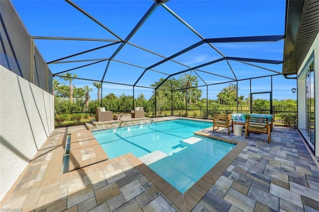 view of pool with glass enclosure, outdoor lounge area, and a patio area