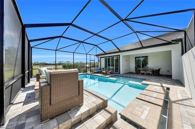 view of swimming pool featuring outdoor lounge area, a patio, and a lanai