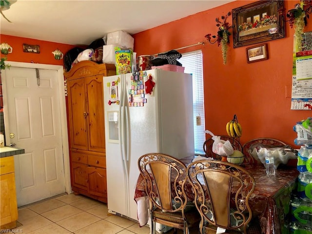 kitchen featuring white refrigerator with ice dispenser and light tile floors