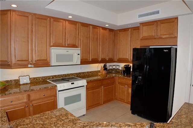 kitchen with dark stone counters, light tile floors, and white appliances