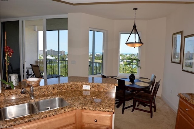 kitchen with pendant lighting, light stone countertops, and sink